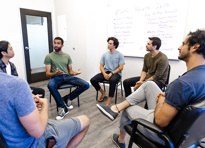 young men sitting in a circle in group therapy session